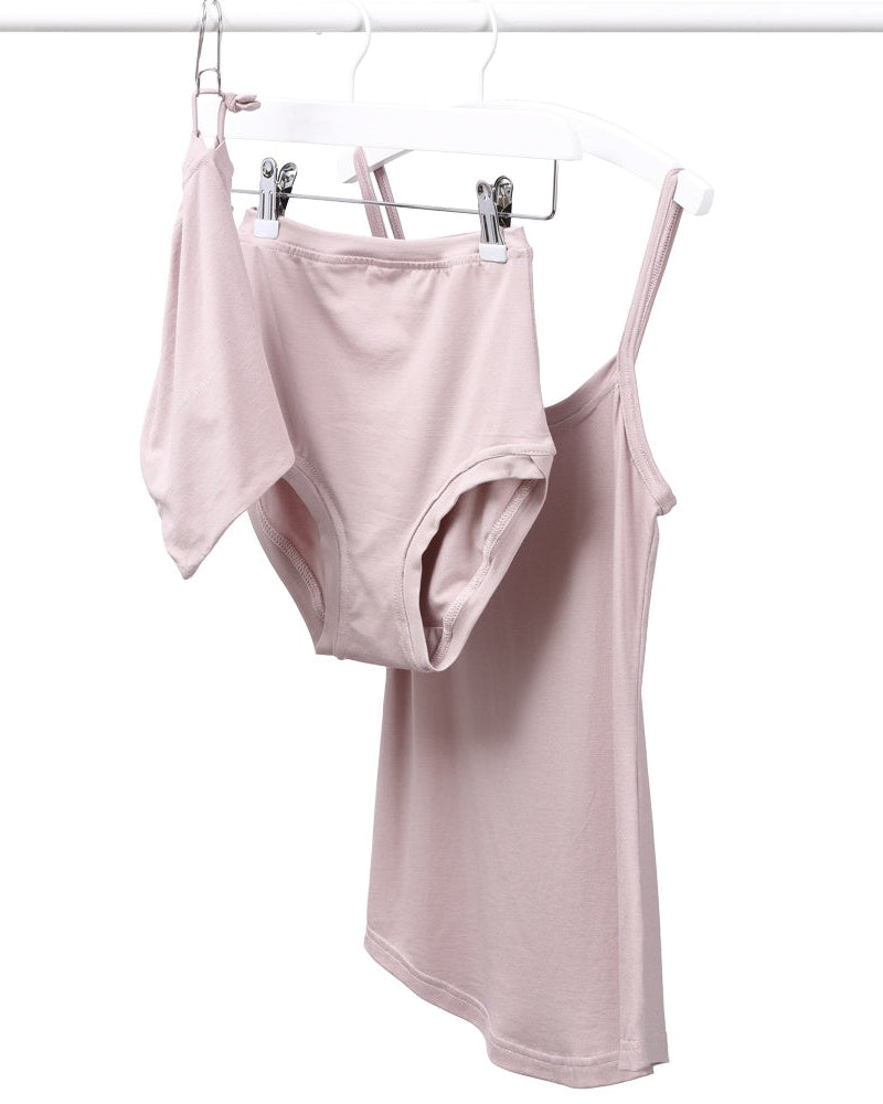 A strappy dusty pink vest and pants set hanging on a rail against a white background.