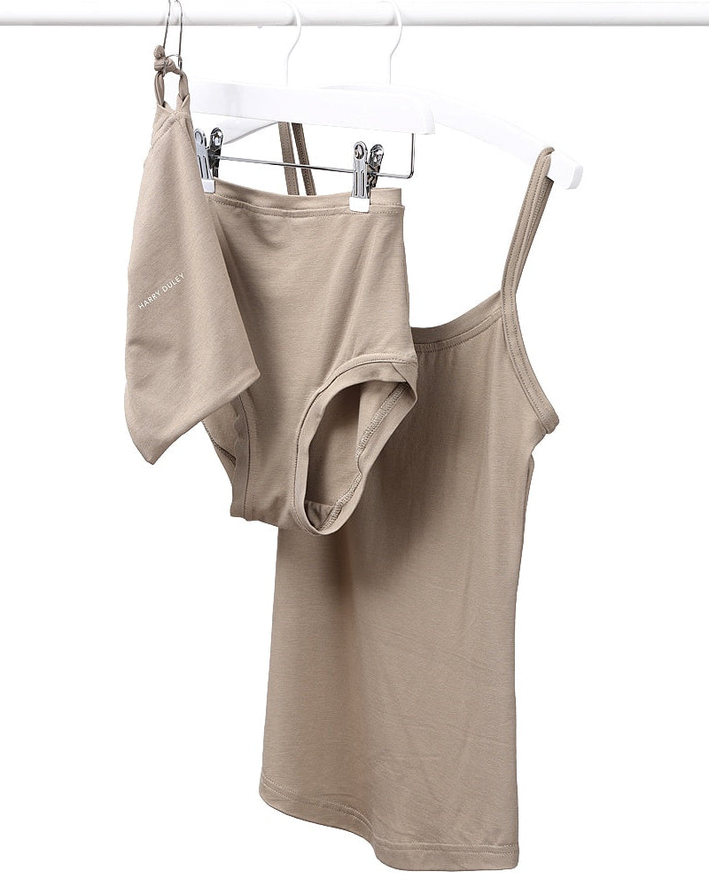 A strappy beige vest and pants set hanging on a white background.